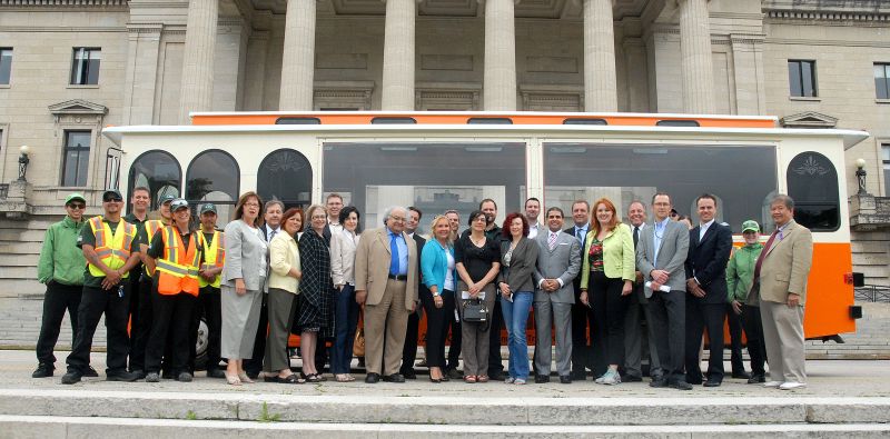Corporate group in front of the Manitoba Legislative Building with the trolley