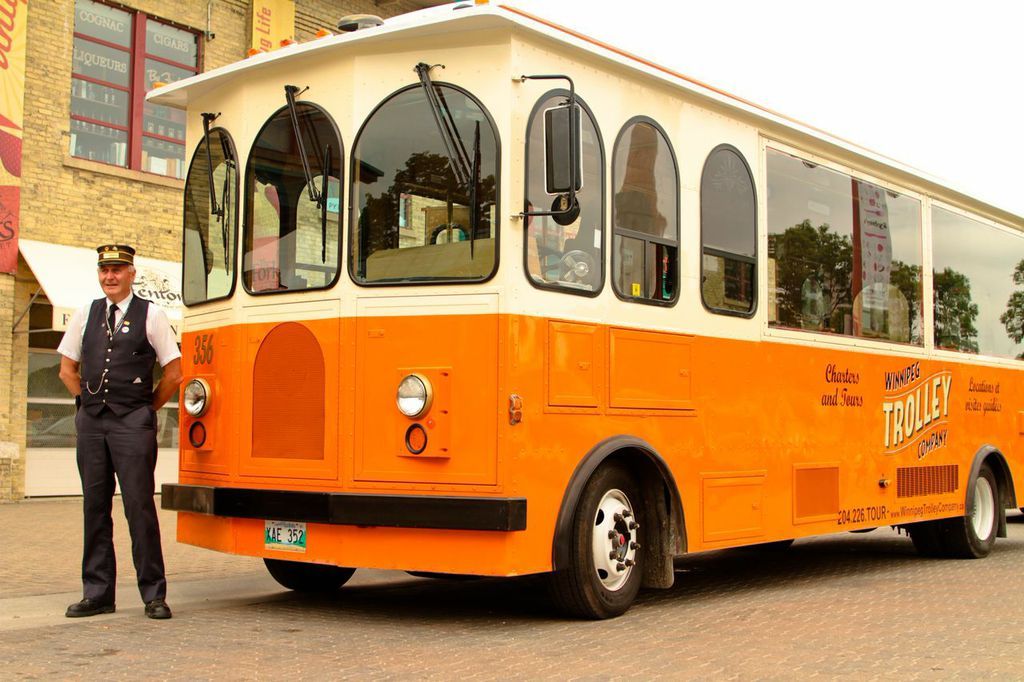 Uniformed trolley driver beside the orange Winnipeg Trolley