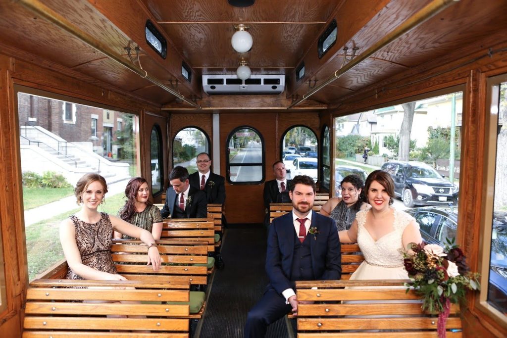 Newlyweds and wedding party seated inside the trolley
