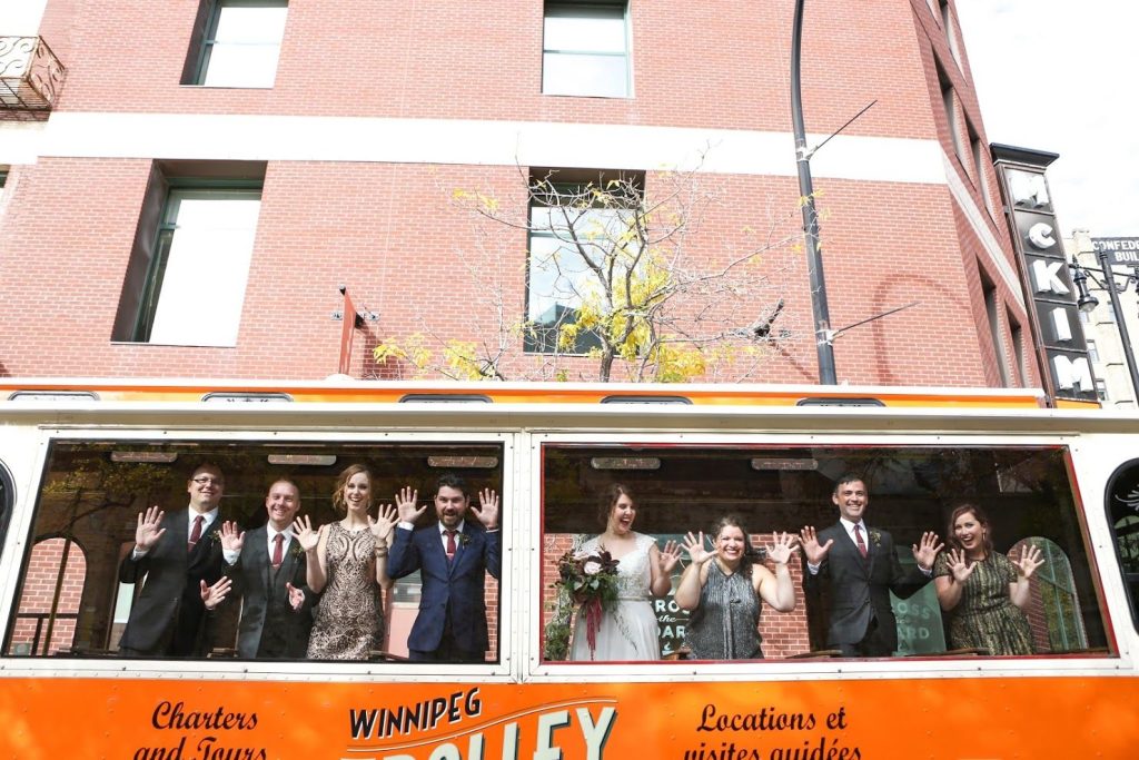 Wedding party waving from the trolley windows